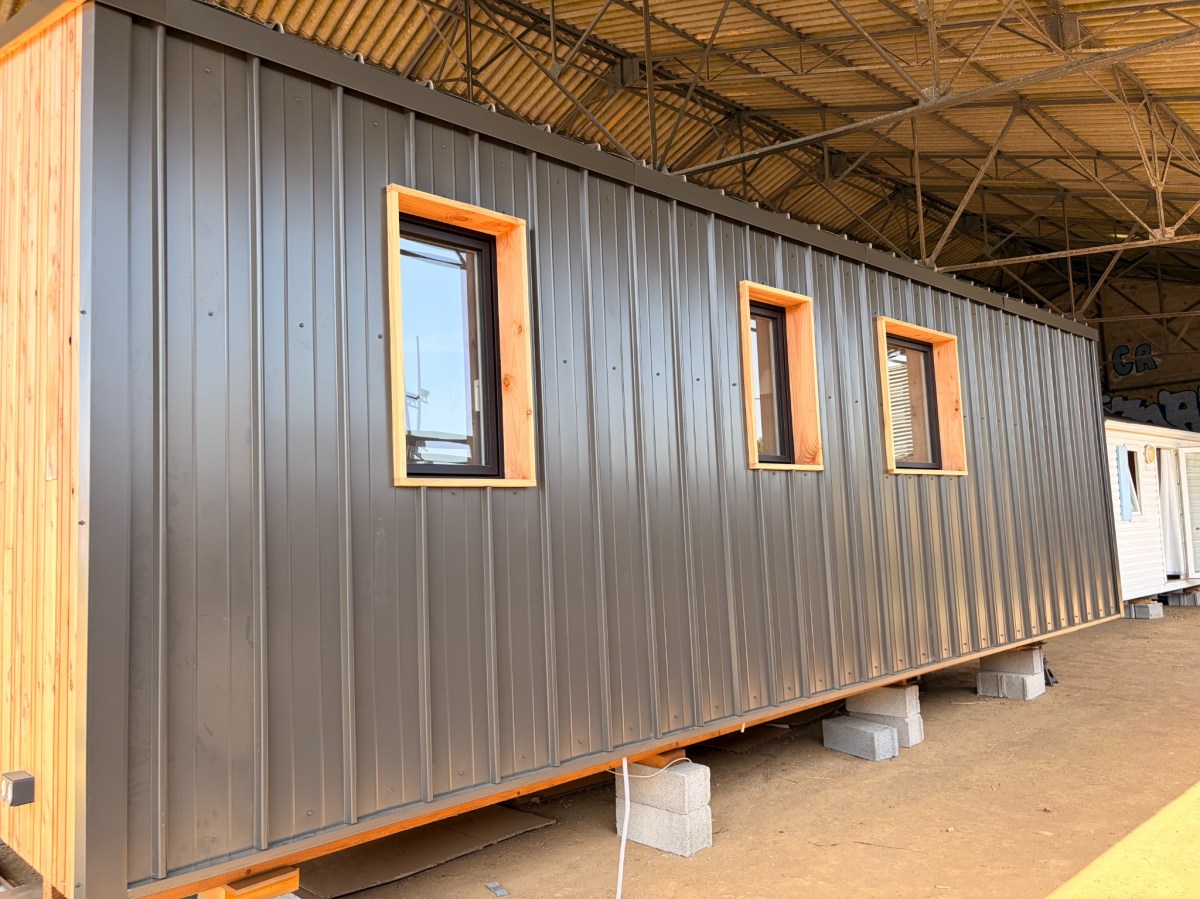 Façade métallique du démonstrateur avec encadrements de fenêtres en bois.