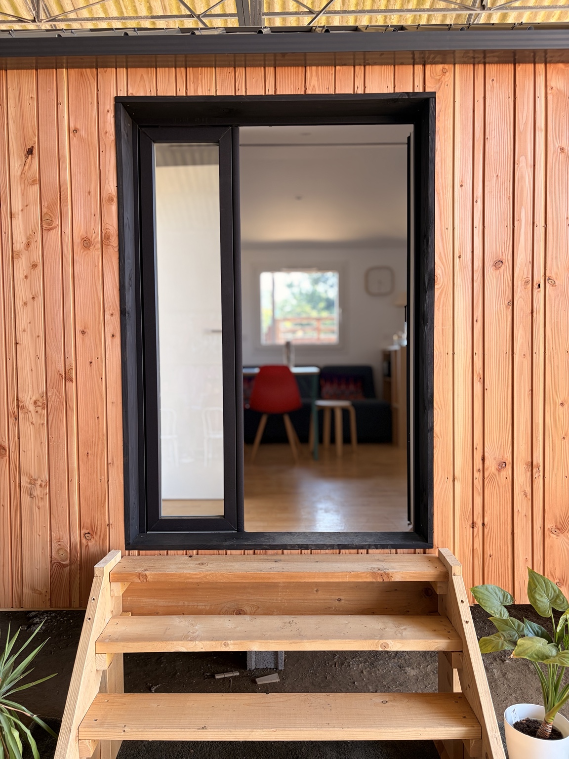 Entrée ouverte du démonstrateur avec escalier en bois et vue vers le séjour.